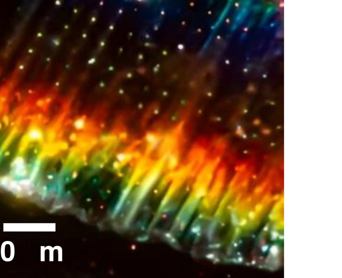 Dark-field micrograph of the edge of a thin diamond membrane, showing interference colors and bright points from individual emitters.